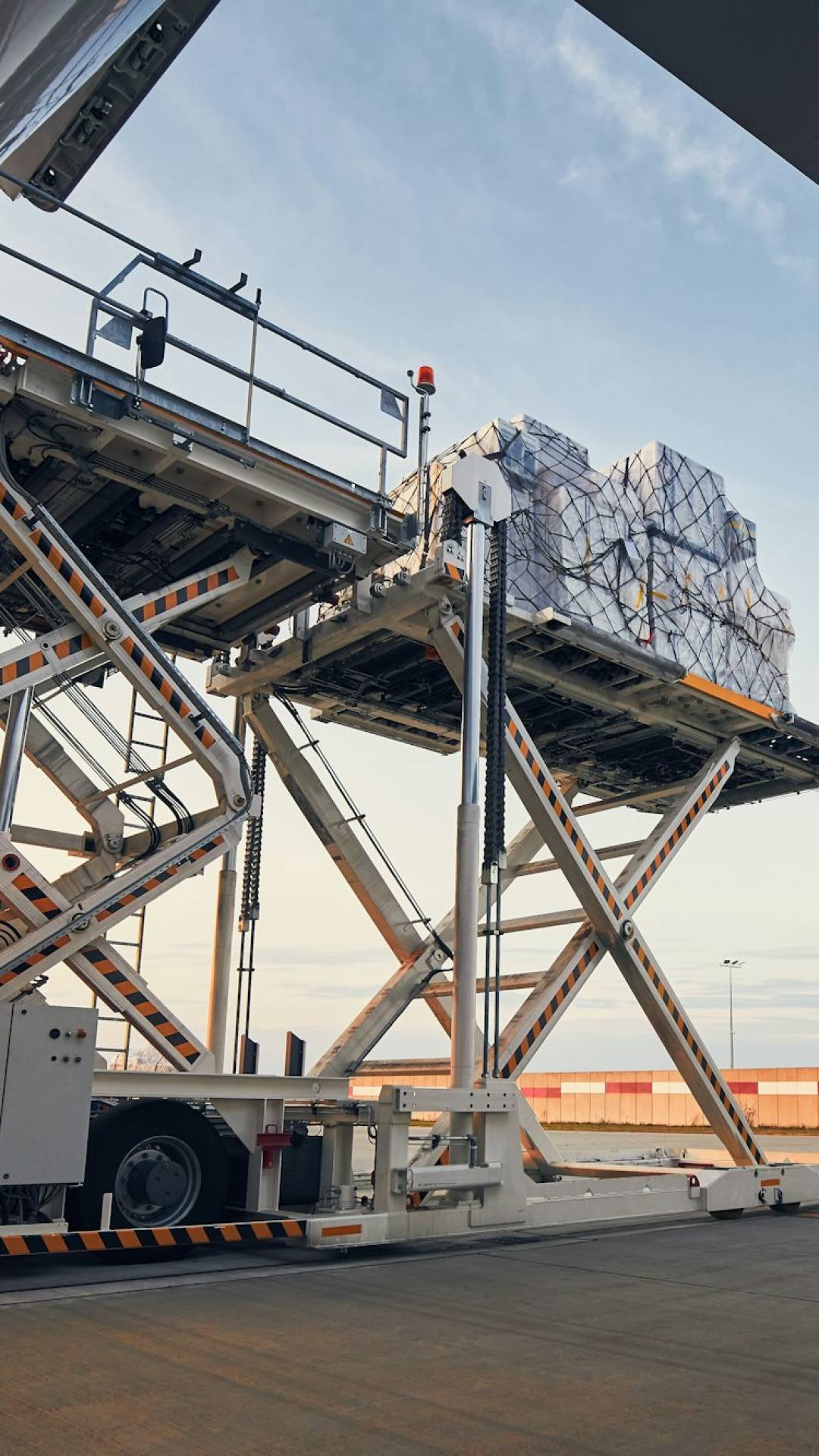 Loading of cargo containers to airplane at sunset